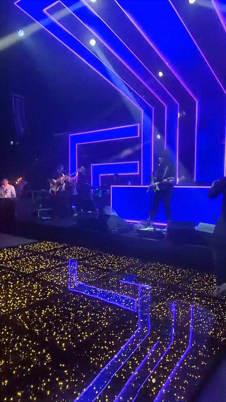 Palco grande de casamento com painéis de luz azul e a banda tocando para o salão iluminado